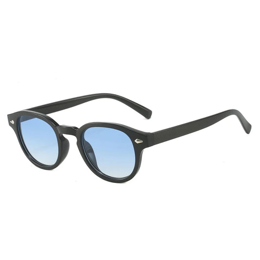 Lunettes de soleil noires modèle Azurea de la collection MILO avec monture épaisse en plastique et verres teintés bleu azur, dotées de petites décorations en forme de triangle métallique au niveau des charnières."