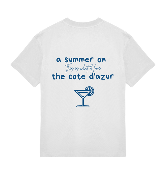 T-shirt blanc Soy Amor vu de dos avec l’inscription “a summer on the côte d’azur”, la phrase manuscrite “This is what I love” et une illustration bleue d’un cocktail avec une tranche de citron.