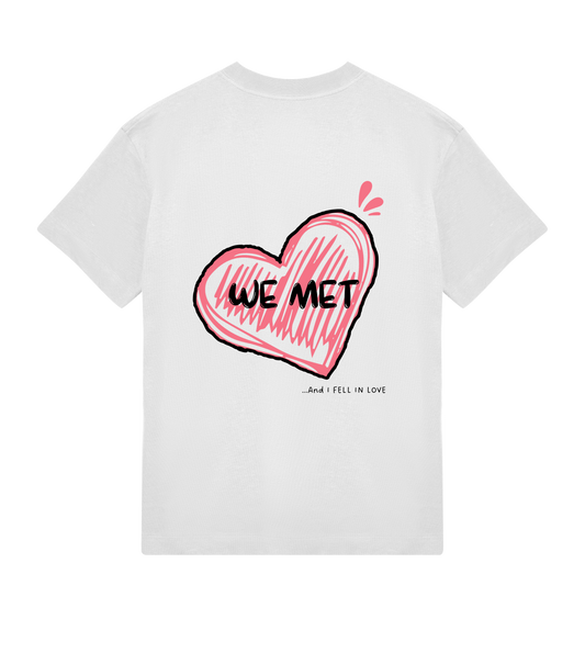 T-shirt blanc Soy Amor vu de dos avec un grand coeur rose dessiné au trait, l’inscription “WE MET” au centre et la phrase “…and I fell in love” écrite en bas.